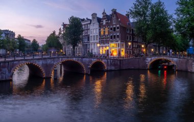 Keizersgracht - Amsterdam, Hollanda alacakaranlıkta kanalda İmparator 'un üzerinde köprü.