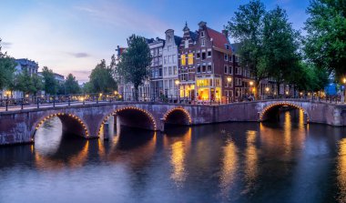 Keizersgracht - Amsterdam, Hollanda alacakaranlıkta kanalda İmparator 'un üzerinde köprü.