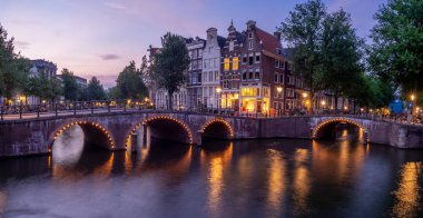 Keizersgracht - Amsterdam, Hollanda alacakaranlıkta kanalda İmparator 'un üzerinde köprü.