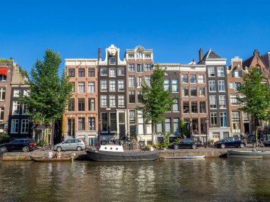 Amsterdam, Hollanda - Temmuz 2018: Binalar ve Amsterdam'ın güzel ve sakin kanallardan gün boyunca merkezi Amsterdam'da boyunca tekne. Kanallar bir Amsterdam'ın ana konumlar vardır.