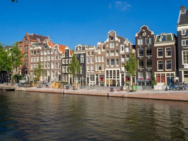 Amsterdam, Hollanda - Temmuz 2018: Binalar ve Amsterdam'ın güzel ve sakin kanallardan gün boyunca merkezi Amsterdam'da boyunca tekne. Kanallar bir Amsterdam'ın ana konumlar vardır.