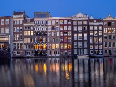 Geleneksel kanal üzerinde Damrak gece karanlığında Amsterdam'da ev sahipliği yapmaktadır. Kanaldaki binalar şimdi çok popüler olan geleneksel Hollanda mimari biçimidir.