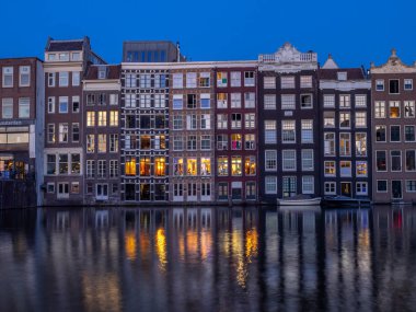 Geleneksel kanal üzerinde Damrak gece karanlığında Amsterdam'da ev sahipliği yapmaktadır. Kanaldaki binalar şimdi çok popüler olan geleneksel Hollanda mimari biçimidir.