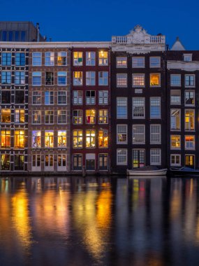 Geleneksel kanal üzerinde Damrak gece karanlığında Amsterdam'da ev sahipliği yapmaktadır. Kanaldaki binalar şimdi çok popüler olan geleneksel Hollanda mimari biçimidir.