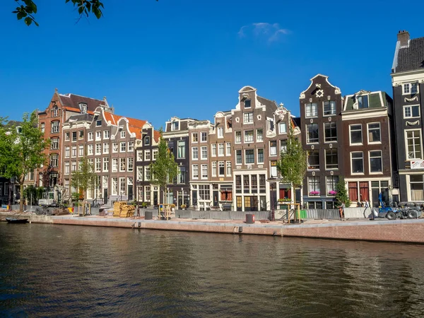 Amsterdam, Hollanda - Temmuz 2018: Binalar ve Amsterdam'ın güzel ve sakin kanallardan gün boyunca merkezi Amsterdam'da boyunca tekne. Kanallar bir Amsterdam'ın ana konumlar vardır.