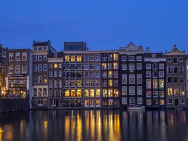 Geleneksel kanal üzerinde Damrak gece karanlığında Amsterdam'da ev sahipliği yapmaktadır. Kanaldaki binalar şimdi çok popüler olan geleneksel Hollanda mimari biçimidir.