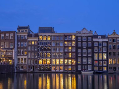 Geleneksel kanal üzerinde Damrak gece karanlığında Amsterdam'da ev sahipliği yapmaktadır. Kanaldaki binalar şimdi çok popüler olan geleneksel Hollanda mimari biçimidir.