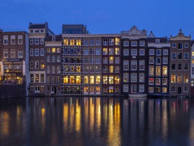 Geleneksel kanal üzerinde Damrak gece karanlığında Amsterdam'da ev sahipliği yapmaktadır. Kanaldaki binalar şimdi çok popüler olan geleneksel Hollanda mimari biçimidir.