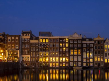 Geleneksel kanal üzerinde Damrak gece karanlığında Amsterdam'da ev sahipliği yapmaktadır. Kanaldaki binalar şimdi çok popüler olan geleneksel Hollanda mimari biçimidir.