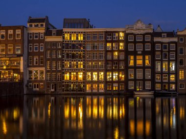 Geleneksel kanal üzerinde Damrak gece karanlığında Amsterdam'da ev sahipliği yapmaktadır. Kanaldaki binalar şimdi çok popüler olan geleneksel Hollanda mimari biçimidir.