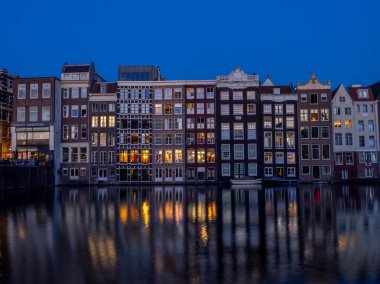 Geleneksel kanal üzerinde Damrak gece karanlığında Amsterdam'da ev sahipliği yapmaktadır. Kanaldaki binalar şimdi çok popüler olan geleneksel Hollanda mimari biçimidir.