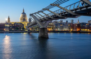Gece karanlığında Thames Nehri kapsayan Millennium Köprüsü. St Paul Katedrali karşı kıyıda yer alır.
