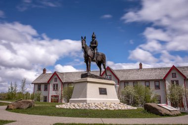 Calgary, Alberta - 8 Mayıs 2019: Fort Calgary önünde Albay James Macleod heykeli. Kırmızı ve beyaz bina arka plandadır. Gün boyu uzun pozlama.