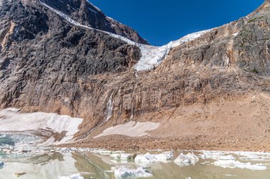 Melek Buzulu Jasper Ulusal Parkı 'ndaki Edith Dağı' nın altındaki bir uçurumda asılı duruyor.