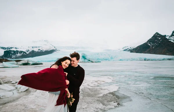 Happy newlyweds walking in cold windy day Glacier Lagoon. Iceland Wedding. — Stock Photo, Image