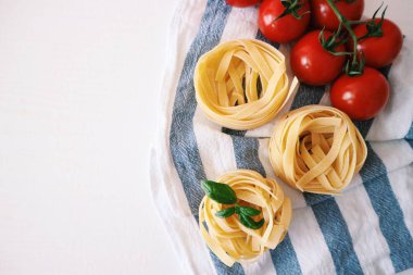 pişmemiş tagliatelle makarna üzerine çizgili kumaş peçete ile kiraz domates