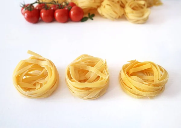 Uncooked Tagliatelle Pasta Cherry Tomatoes White Table Surface — Stock Photo, Image