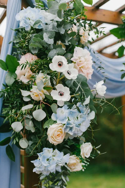 Mavi kumaş ve ahşap elemanları bir rustik düğün töreninde çiçek kemer