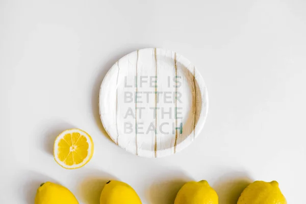 Paper plate, lemons on white background. Picnic at the beach concept. Flat lay, top view
