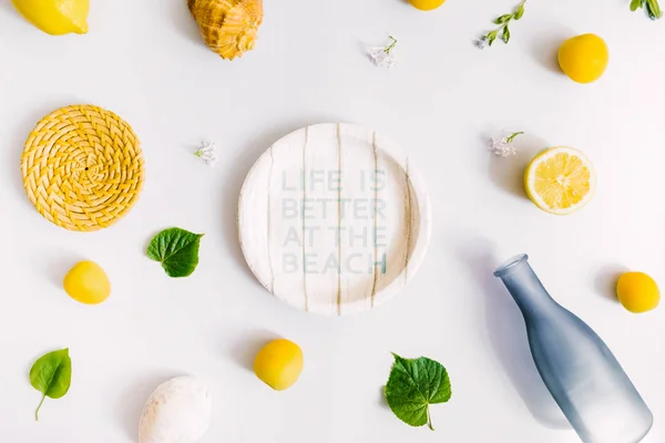 Paper plate, lemons, bottle and picnic stuff on white background. Picnic at the beach concept. Flat lay, top view