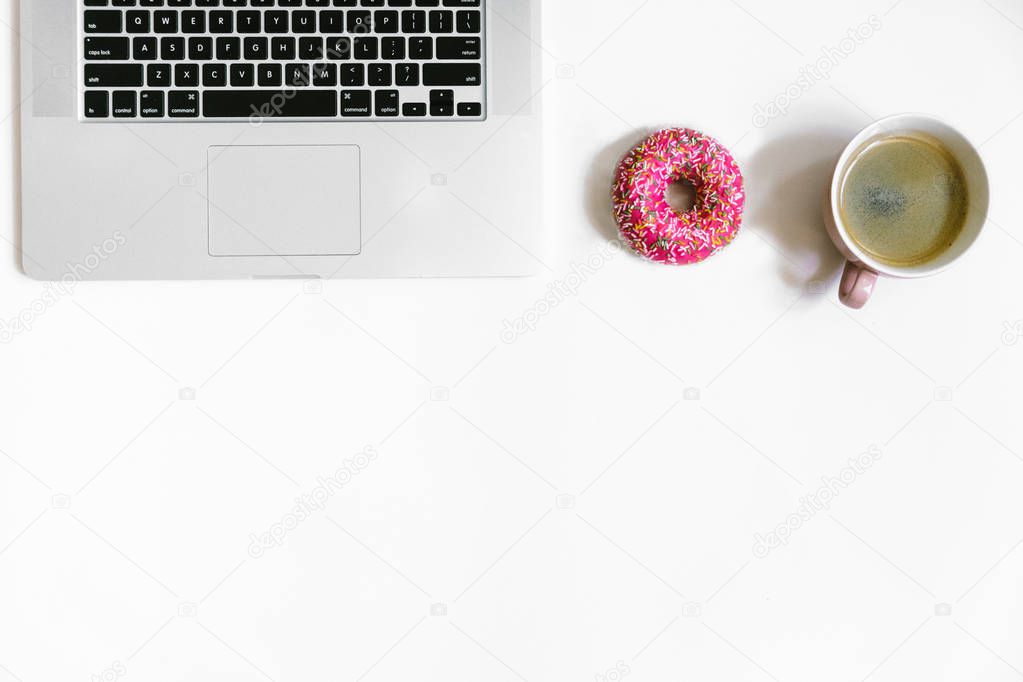 Feminine desktop close up, laptop keyboard, cup of coffee and donut, feminine accessories. Flat lay composition, white background. 