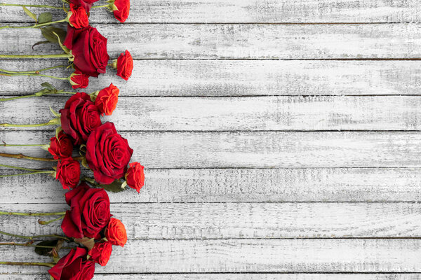 Top view of beautiful red roses on grungy grey wooden table with copy space