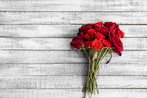 Top view of beautiful red roses bouquet on grungy grey wooden table with copy space