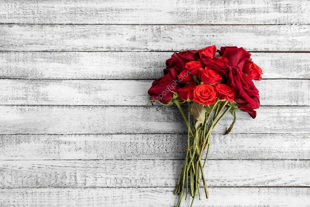 Top view of beautiful red roses bouquet on grungy grey wooden table with copy space