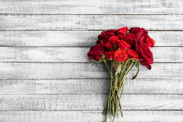 Top view of beautiful red roses bouquet on grungy grey wooden table with copy space — Stock Photo