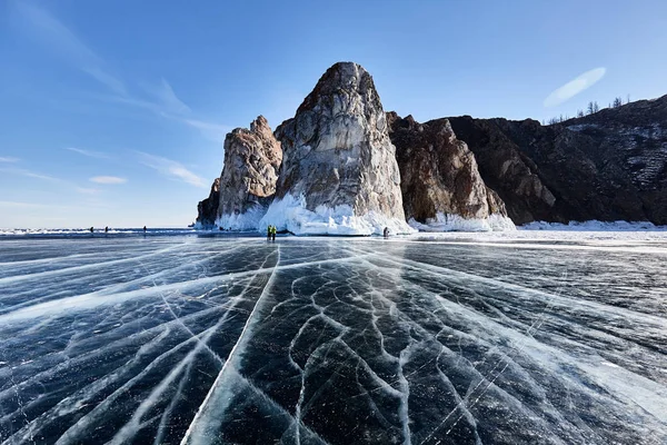 Lake Baikal in winter. Beautiful rocky island on a background of blue sky and smooth ice with cracks