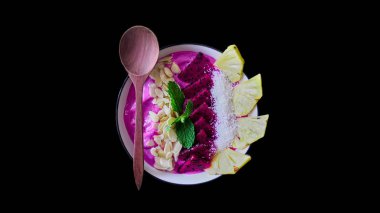 Pitaya smoothie kahvaltı kase ejderha meyve, nane, badem gevreği, chia tohumu, ananas ile tepesinde. Peçete ve kaşıkla besleyici yaz yemeği. Üstte yalıtılmış görünüm.