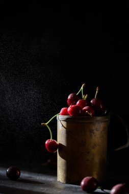 Bakır bardakta kiraz çileği, arka planda sprey..