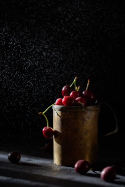Bakır bardakta kiraz çileği, arka planda sprey..