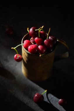 Bakır bardakta kiraz çileği, arka planda sprey..