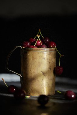 Bakır bardakta kiraz çileği, arka planda sprey..