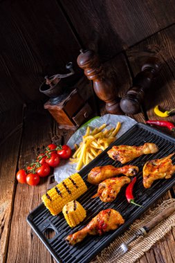 Rustik ızgara tavuk kanatlar, bacaklar ve baharatlı Mısır