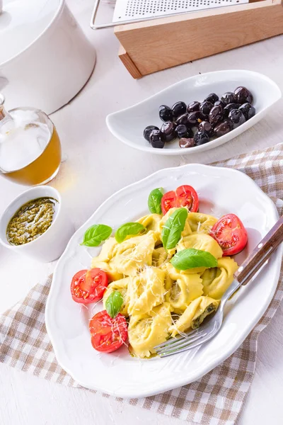 Ravioli ıspanak doldurma, rendelenmiş peynir ve beyaz plaka kokteyl domates ile