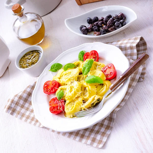 Ravioli ıspanak doldurma, rendelenmiş peynir ve beyaz plaka kokteyl domates ile