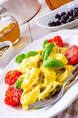 Ravioli ıspanak doldurma, rendelenmiş peynir ve plaka üzerinde kokteyl domates ile