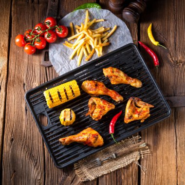 Rustik ızgara tavuk kanatlar, bacaklar ve baharatlı Mısır