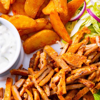 Gyros plaka yeşil salata ve patates dilimleri ve et dilimleri ile 