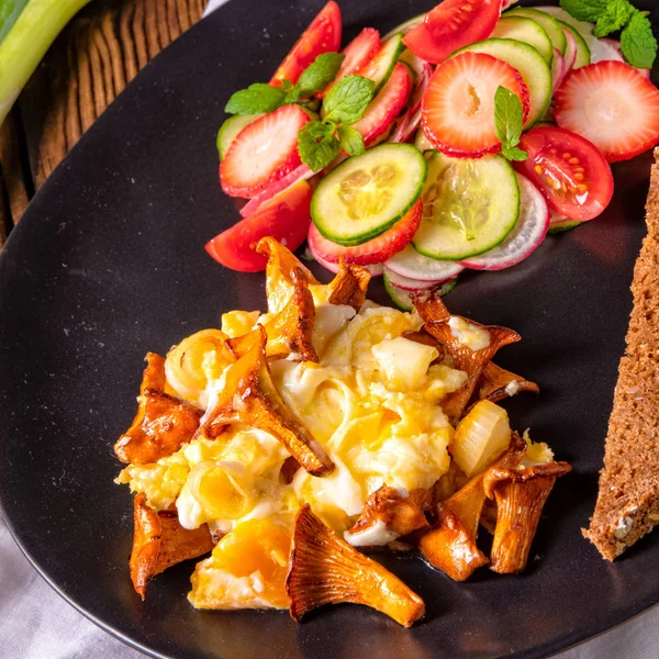スクランブルエッグと皿の上のパンとグリーン サラダ新鮮なアンズタケ — ストック写真