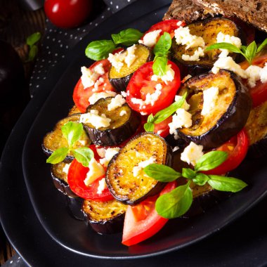 Aromatik beyaz peynir ve domates siyah plaka üzerinde ızgara patlıcan yakın çekim 