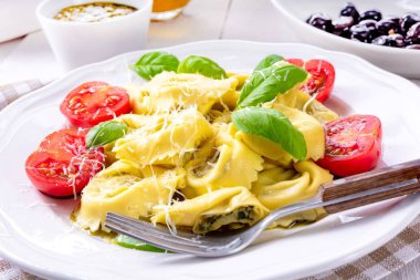 Ravioli ıspanak doldurma ve beyaz tabakta domates rendelenmiş peynir ile yakın çekim 