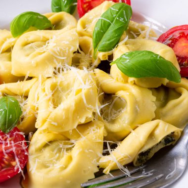 Ravioli ıspanak doldurma ve beyaz tabakta domates rendelenmiş peynir ile yakın çekim 