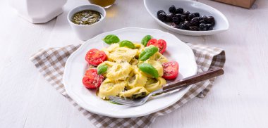 Ravioli ıspanak doldurma ve beyaz tabakta domates rendelenmiş peynir ile yakın çekim 