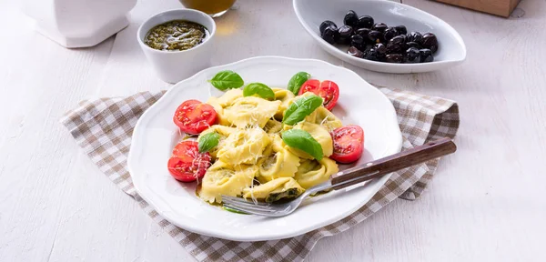 Ravioli ıspanak doldurma ve beyaz tabakta domates rendelenmiş peynir ile yakın çekim 