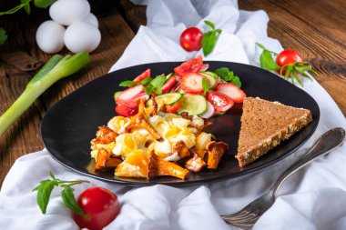 Sahanda yumurta ve ekmek plaka ile yeşil salata ile taze chanterelles 