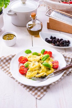 Ravioli ıspanak doldurma, rendelenmiş peynir ve beyaz plaka kokteyl domates ile