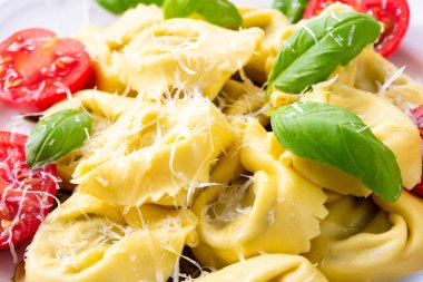 Ravioli ıspanak doldurma, rendelenmiş peynir ve beyaz plaka kokteyl domates ile